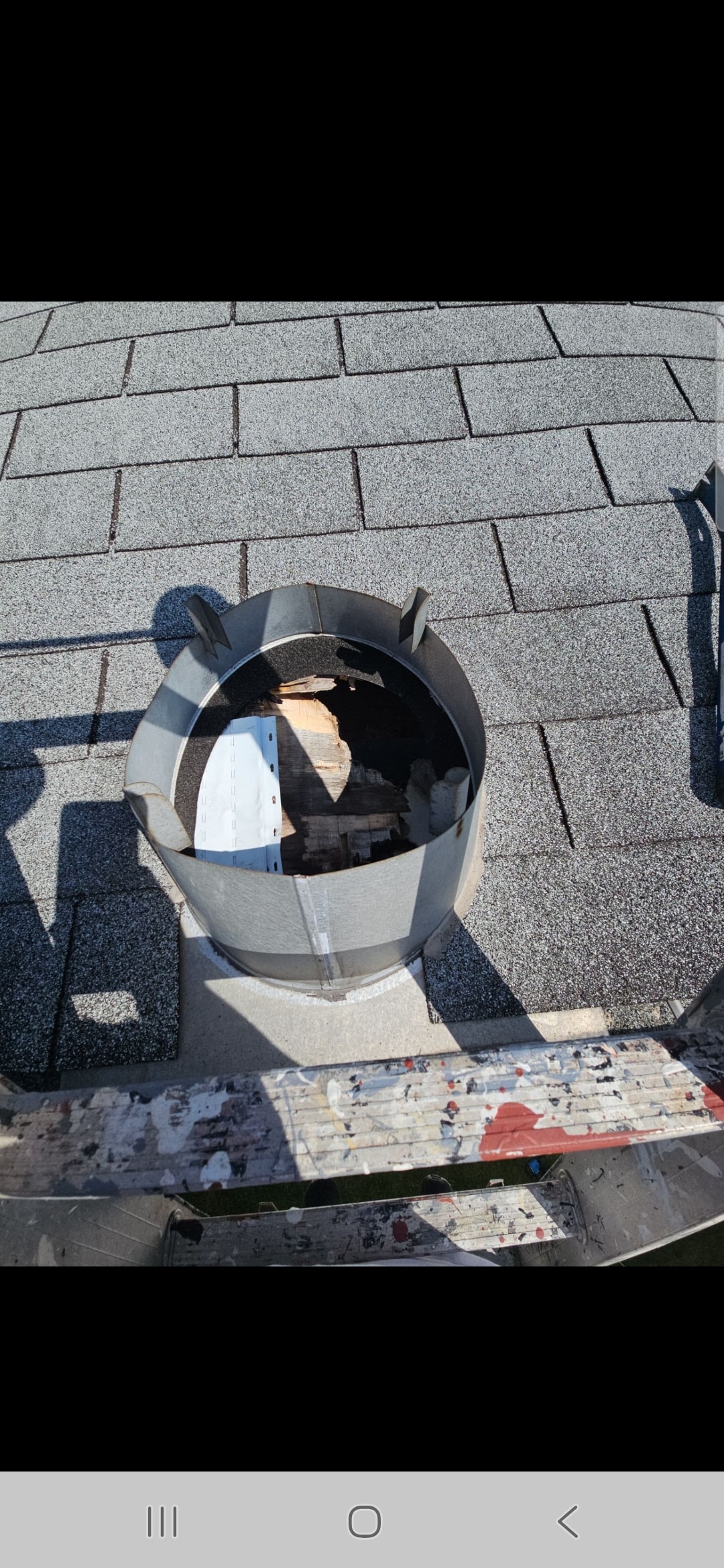 Emergency roof repair — open chimney flashing on asphalt shingle roof mid-repair
