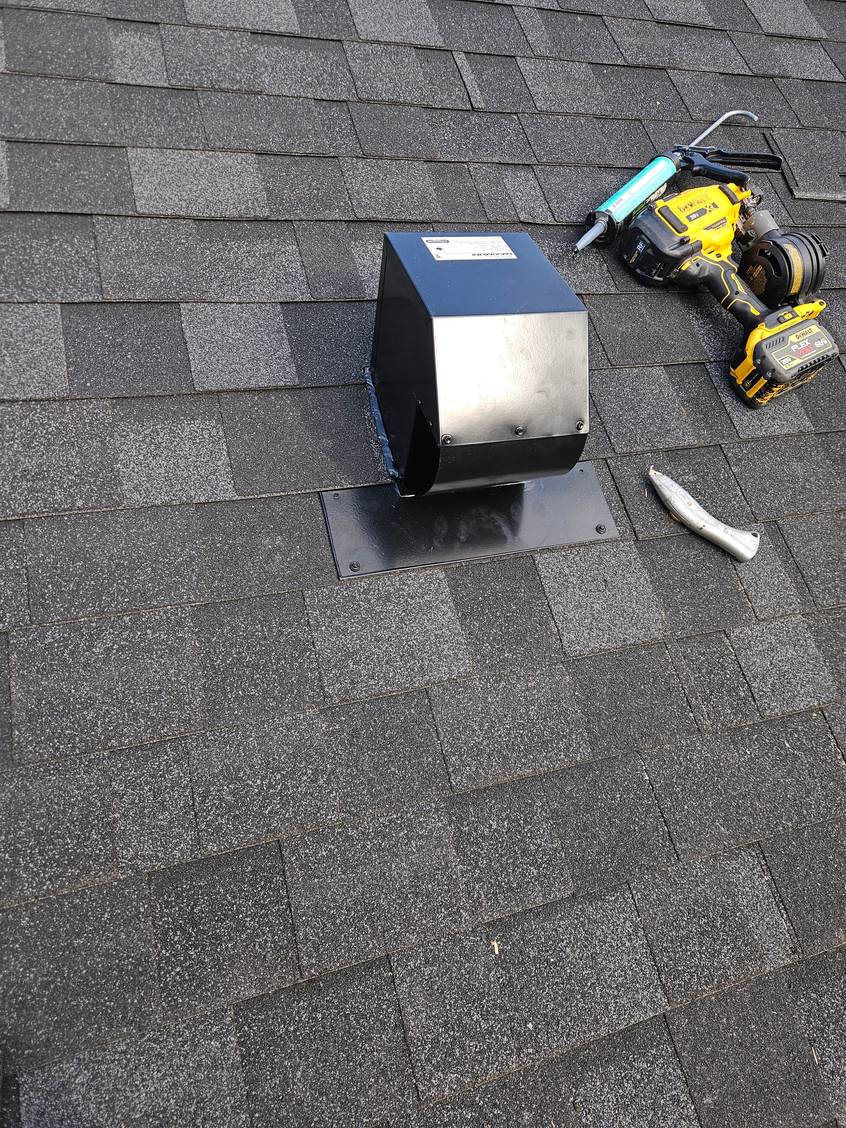 CT6 roof vent cap freshly installed on asphalt shingles with DeWalt drill on roof